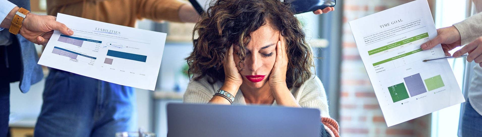  Krakenimages.com (Foto: Adobe Stock, Junge Frau stützt überfordert den Kopf in die Hände, sie sitzt im Büro vor einem Laptop, um sie herum strecken ihr Menschen Arbeitsutensilien entgegen. Symbolbild für Überstunden und Mehrarbeit im Job, die überfordert.)