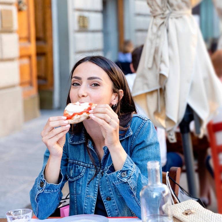Eine Frau isst Pizza in Italien.