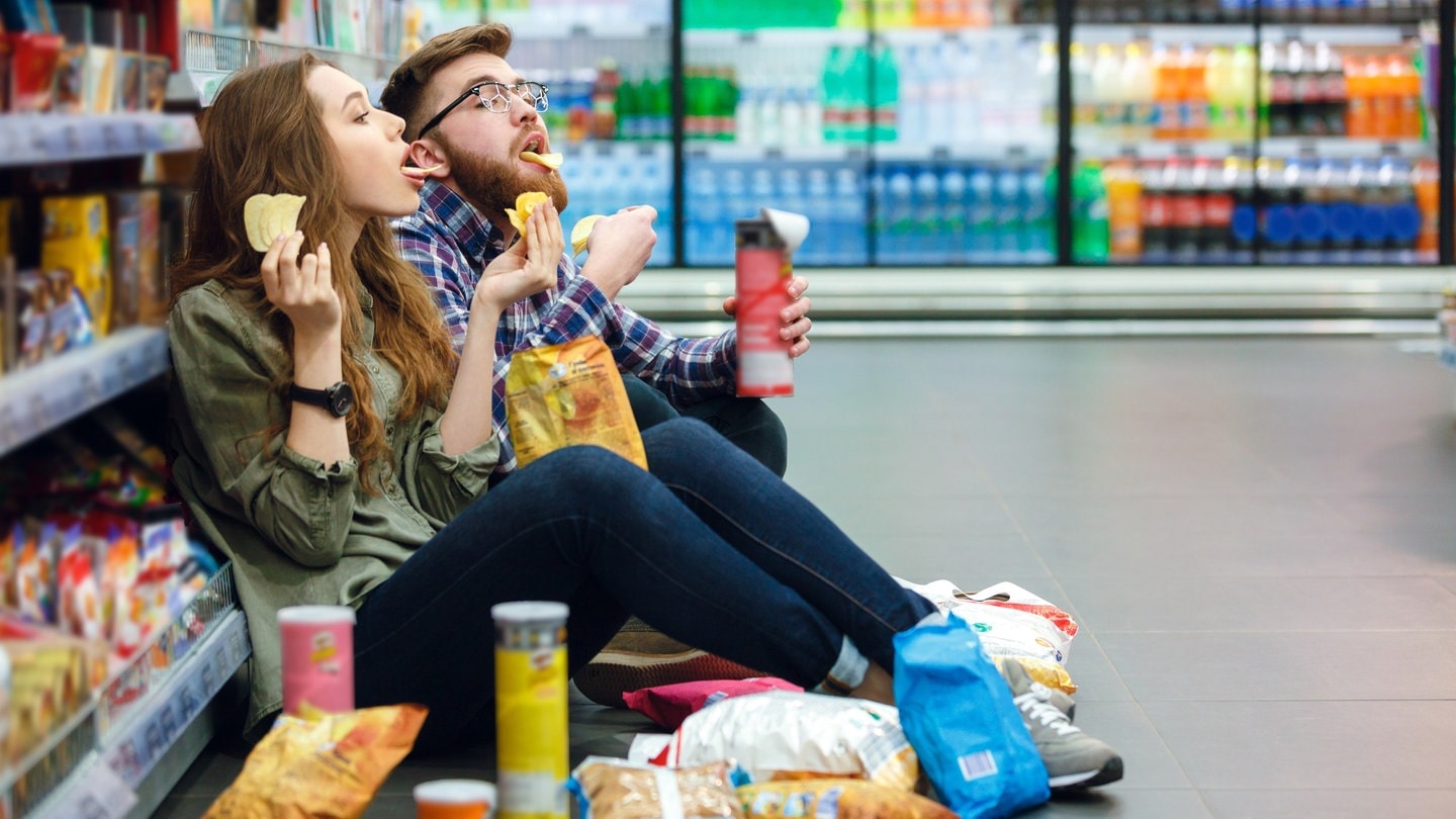 Mann und Frau naschen im Supermarkt (Foto: AdobeStock)