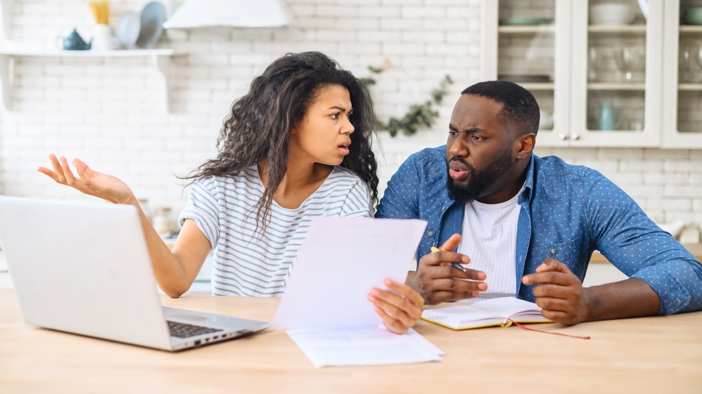 Ein Mann und eine Frau sitzen am Küchentisch und sind entsetzt von einer Rechnung. (Foto: Adobe Stock, Vadim Pastuh)