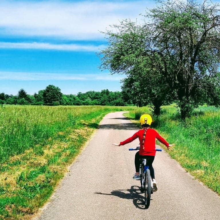 Ein Kind auf einem Fahrrad fährt auf einem Feldweg bei gutem Wetter