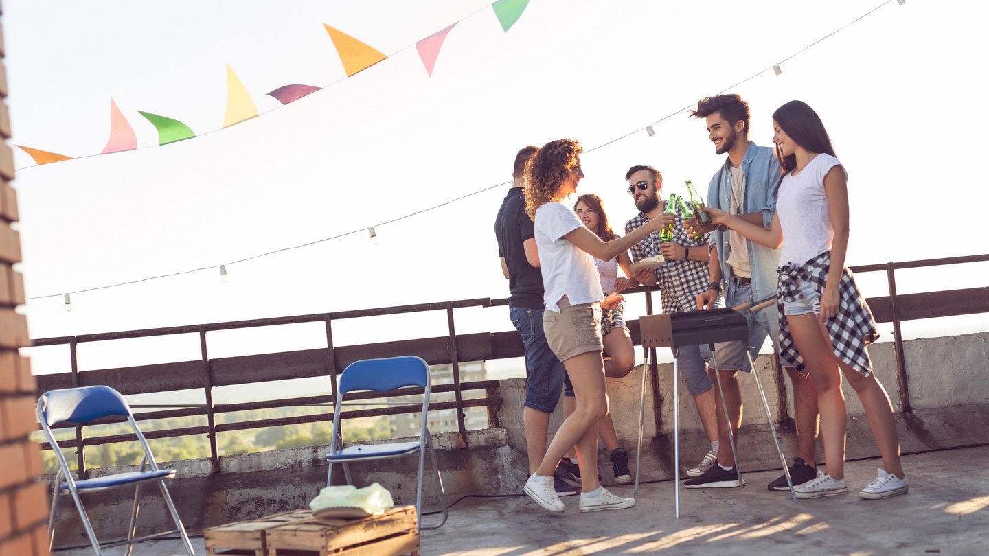 Junge Menschen grillen auf dem Balkon bei abendlicher Sonneneinstrahlung (Foto: Adobe Stock, Impact Photography)