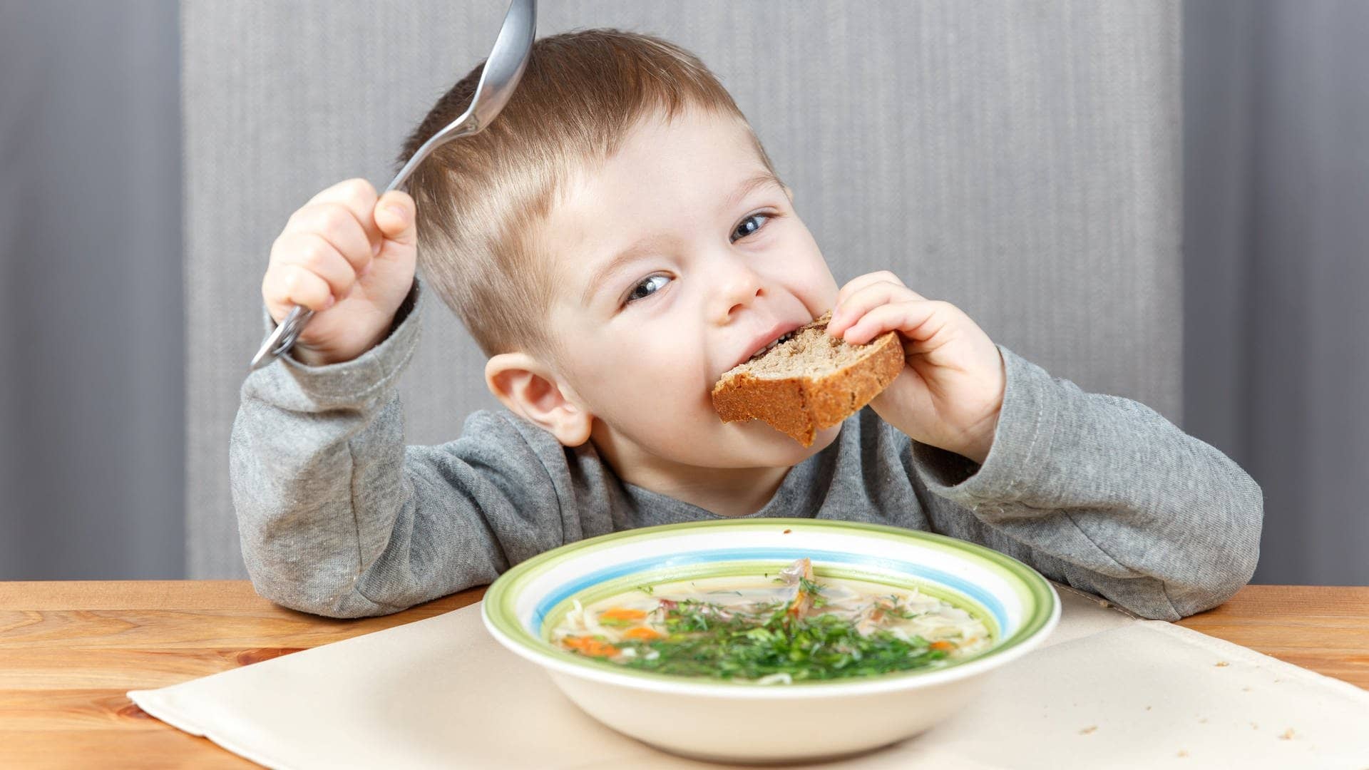 Kleiner Junge löffelt Hühnersuppe und steckt sich ein Stück Brot in den Mund. Das hilft sicher gegen Erkältung. (Foto: Adobe Stock, Vanoa2)