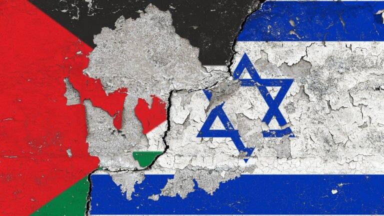 Ein Symbolfoto zum Nahostkonflikt über den wir im Interview mit einem jungen Journalist aus Israel gesprochen haben. Das Bild zeigt Die Flaggen von Palästina und Israel auf einer Wand mit aufgeplatzter Farbe und einem schraegen, dicken Riss.