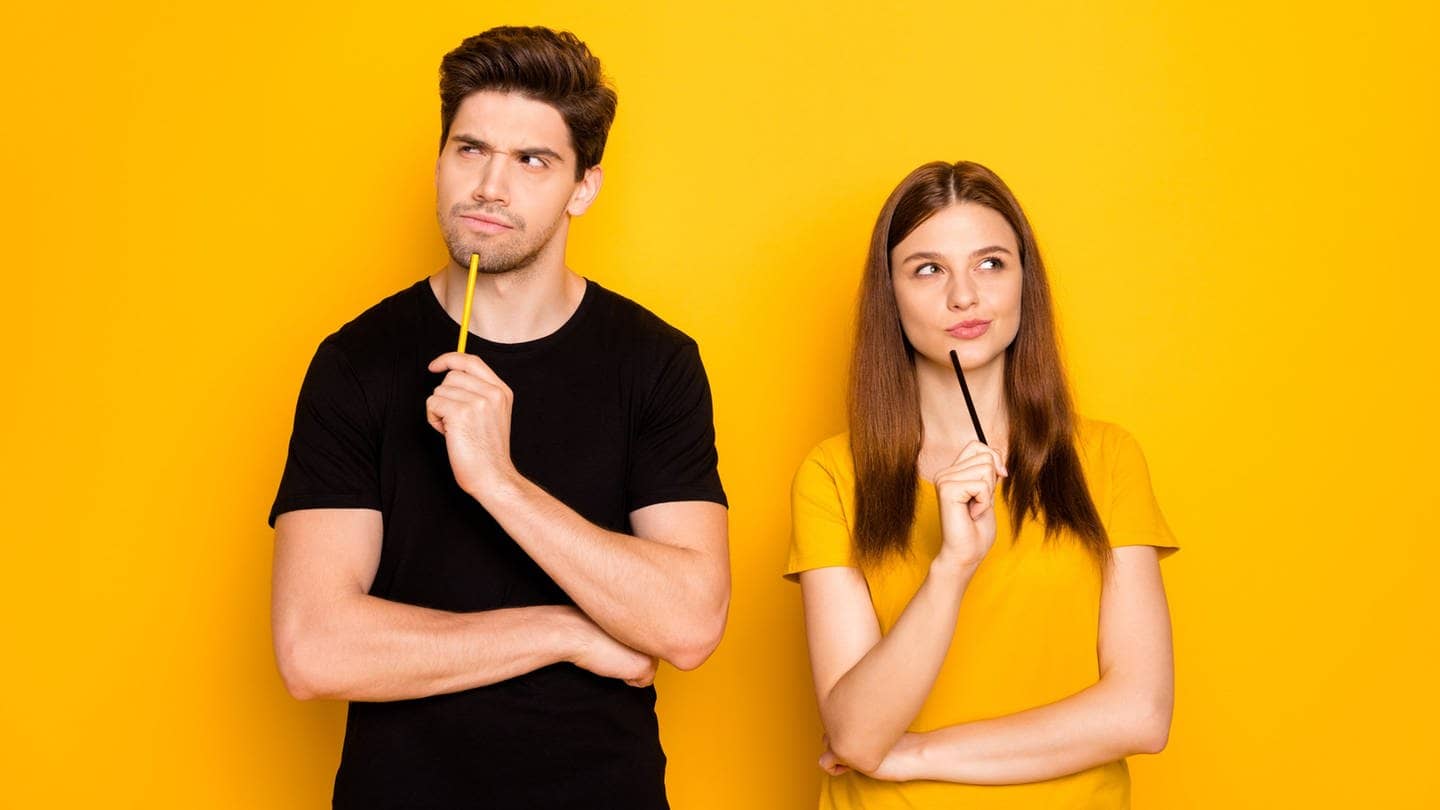 Ein junger Mann und eine junge Frau machen ein grübelndes, nachdenkliches Gesicht. In der Hand halten sie Stifte, als würden gemeinsam das Plural-Quiz machen.