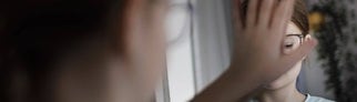 Ein Kind bedeckt sein Spiegelbild mit der Hand.