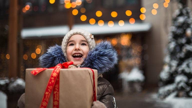 Tolle Geschenkideen: Ein Kind freut sich über ein Geschenk an Weihnachten.