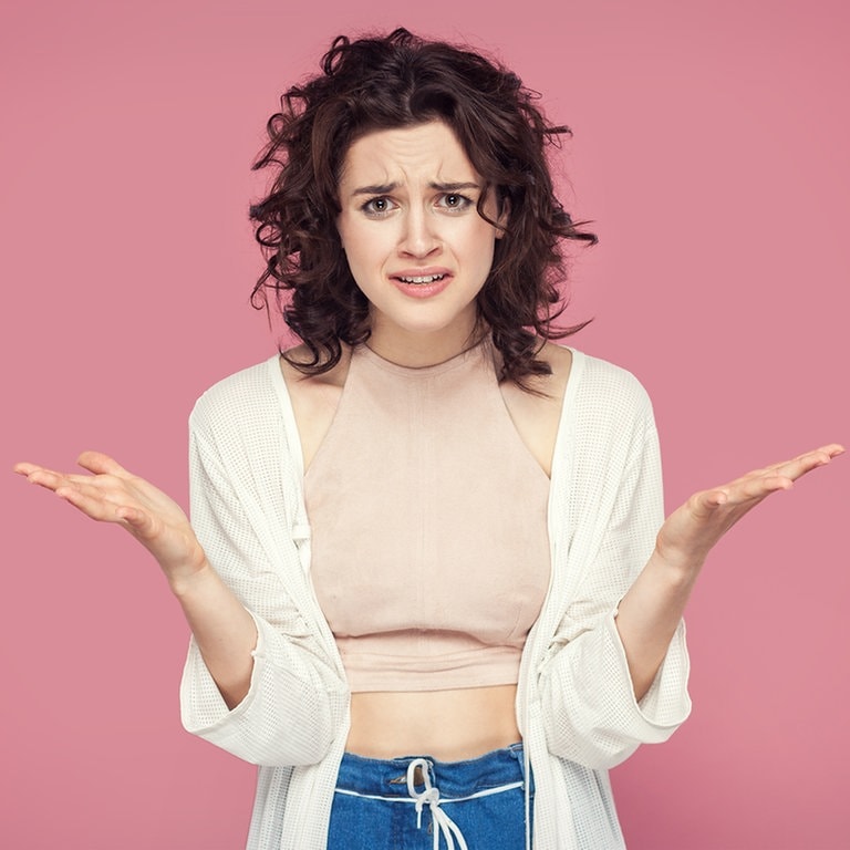 Entscheidungen treffen kann schwer sein. Vielleicht geht es auch der braunhaarigen Frau vor dem rosa Hintergrund, die eine fragende Pose einnimmt, auch so. (Foto: Adobe Stock, khosrork)