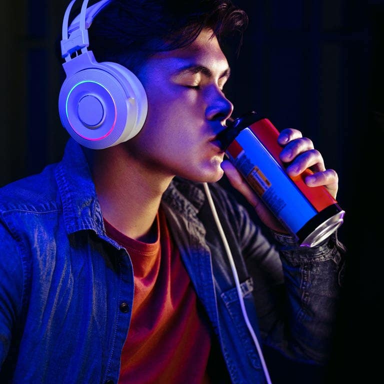 Ein Jugendlicher trinkt einen Energy Drink um sich beim Gaming wachzuhalten.