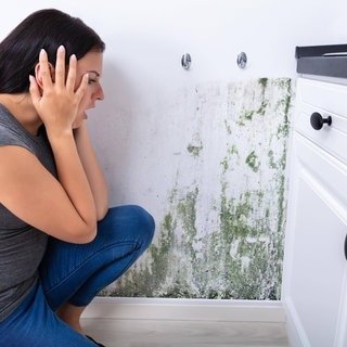 Frau erschrickt sich vor Schimmel an der Wand