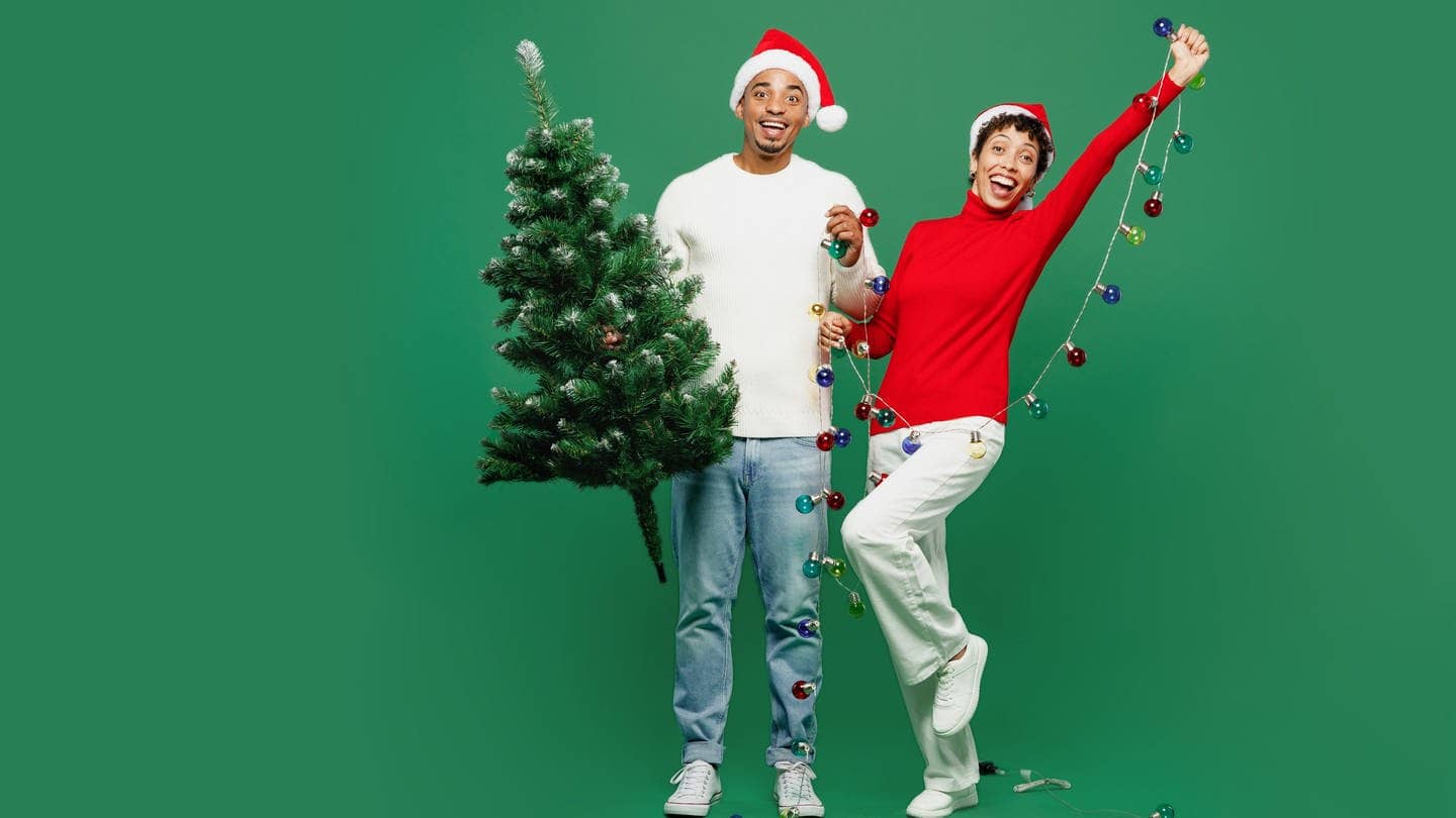 Ein Mann hält einen Weihnachtsbaum in der Hand, neben ihm steht eine Frau und sie überlegen, ob ein Tannenbaum aus Plastik eventuell eine nachhaltige Alternative ist.