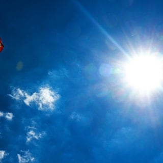 Sonne brennt, Sonnenschirm und blauer Himmel