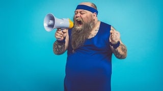 Mann im Trainingsanzug und Megaphone. Bauchfett verlieren: Mit diesen 3 Tipps wirds einfacher!