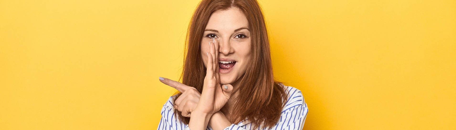 Junge Frau hält ihre Hand seitlich an den Mund, um eine unpopuläre Meinung zu verraten (Foto: Adobe Stock, Asier)