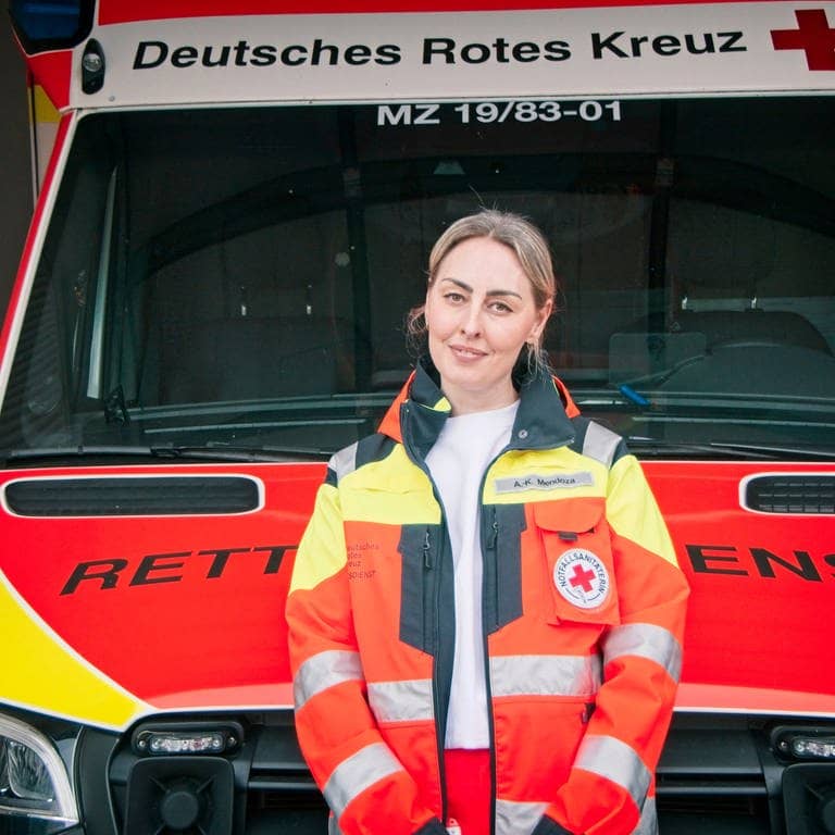 Anne Mendoza steht vor einem Krankenwagen. Sie ist Notfallsanitäterin und Leiterin der Rettungswache in Nieder-Olm, in der Nähe von Mainz. Seit sie 18 ist, fährt sie Rettungseinsätze.Sie sagt, Gewalt gegen Rettungskräfte kennt jede Einsatzkraft.