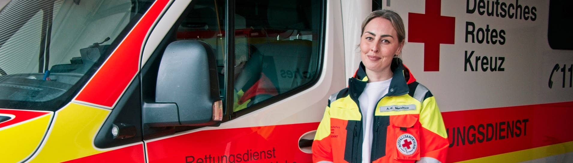 Anne Mendoza steht vor einem Krankenwagen. Sie ist Notfallsanitäterin und Leiterin der Rettungswache in Nieder-Olm, in der Nähe von Mainz. Seit sie 18 ist, fährt sie Rettungseinsätze.Sie sagt, Gewalt gegen Rettungskräfte kennt jede Einsatzkraft. (Foto: SWR, Ferdinand Vögele)