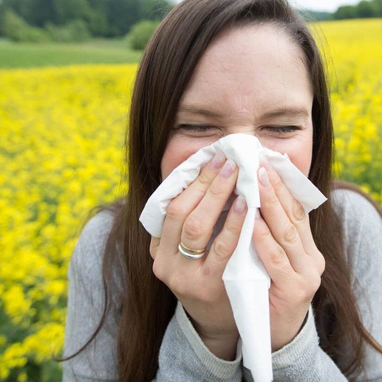 Pollen sind lästig – junge Frau mit Allergie putzt sich die Nase (Foto: dpa Bildfunk, Picture Alliance)