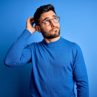Junger Mann mit Brille und blauem Pullover schaut nachdenkend in die Luft. Symbolbild für Sätze, die du nur verstehst, wenn du Dialekt sprichst.