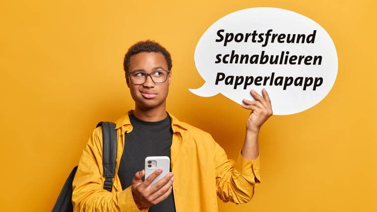 Ein junger Mann hält ein Handy in der einen Hand und in der anderen Hand eine Sprechblase mit den Wörtern Sportsfreund, schnabulieren und Papperlapapp.