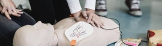 Junge Frau ist über eine Puppe gebeugt und setzt Tipps zur Ersten Hilfe um, indem sie eine Reanimation durchführt