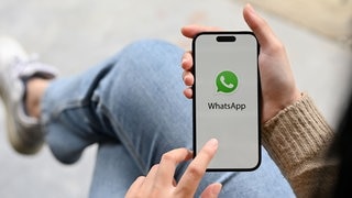 Junge Frau mit Smartphone in der Hand. Beim Messenger Whatsapp können Sprachnachrichten bald in Text umgewandelt und transkribiert werden.