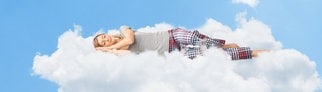 Junge Frau liegt auf Wolken und schläft. Symbolbild für den Selbsttest optimale Schlafdauer: Wie viel Schlaf brauchst du wirklich?