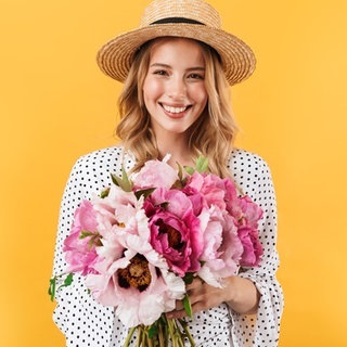 Junge Frau mit Sonnenhut und einem Strauß Blumen in der Hand. Symbolbild für Sprüche, mit denen wir es durch die Blume sagen können, offiziell freundlich.