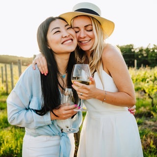 Zwei Frauen nehmen sich mit einem Glas Wein in den Arm | Symbolbild: Gibt es „guten“ Wein ohne Alkohol?