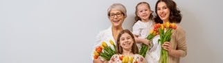 Oma, Mutter und Töchter haben Tulpen in der Hand und gratulieren sich zum Muttertag. 