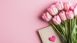 Tulpen und ein Brief mit Herz. Symbolbild für lustige und schöne Whatsapp-Sprüche und Grüße an Mama zum Muttertag.