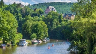 Blick auf das Lahntal bei Nassau mit Kanufahrern, Schiffen und Fachwerkhäusern. In Baden-Württemberg und Rheinland Pfalz gibt es wunderschöne Stand-Up-Paddle Routen. Stiftung Warentest hat 10 SUP-Boards getestet (Foto: IMAGO, IMAGO / Volker Preußer) Blick auf das Lahntal bei Nassau mit Kanufahrern, Schiffen und Fachwerkhäusern. In Baden-Württemberg und Rheinland Pfalz gibt es wunderschöne Stand-Up-Paddle Routen. Stiftung Warentest hat 10 SUP-Boards getestet