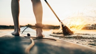 Nahaufnahme eines Stand-Up-Paddlers mit der Leash, der Sicherheitsleine am Fußknöchel. Stiftung Warentest hat SUPs getestet und betont, dass man nie ohne Leash fahren sollte. (Foto: Adobe Stock, yossarian6) Nahaufnahme eines Stand-Up-Paddlers mit der Leash, der Sicherheitsleine am Fußknöchel. Stiftung Warentest hat SUPs getestet und betont, dass man nie ohne Leash fahren sollte.