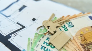 Ein Schlüssel liegt auf einem Grundrissplan einer Wohnung. Mieter werden teilweise bei der Wohnungssuche mit illegalen Vermittlungsprovisionen abgezockt.