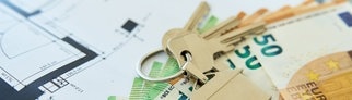 Ein Schlüssel liegt auf einem Grundrissplan einer Wohnung. Mieter werden teilweise bei der Wohnungssuche mit illegalen Vermittlungsprovisionen abgezockt.