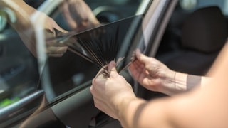 Mit Sonnenschutz die Hitze im Auto bekämpfen. An einem Auto wird eine getönte Folie angebracht. (Foto: Adobe Stock, zphoto83) Mit Sonnenschutz die Hitze im Auto bekämpfen. An einem Auto wird eine getönte Folie angebracht.