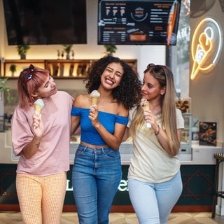 Drei Frauen in einer Eisdiele mit Eis in der Hand. Sehr glücklich, da sie die Tipps für eine leckere Eisdiele kennen.