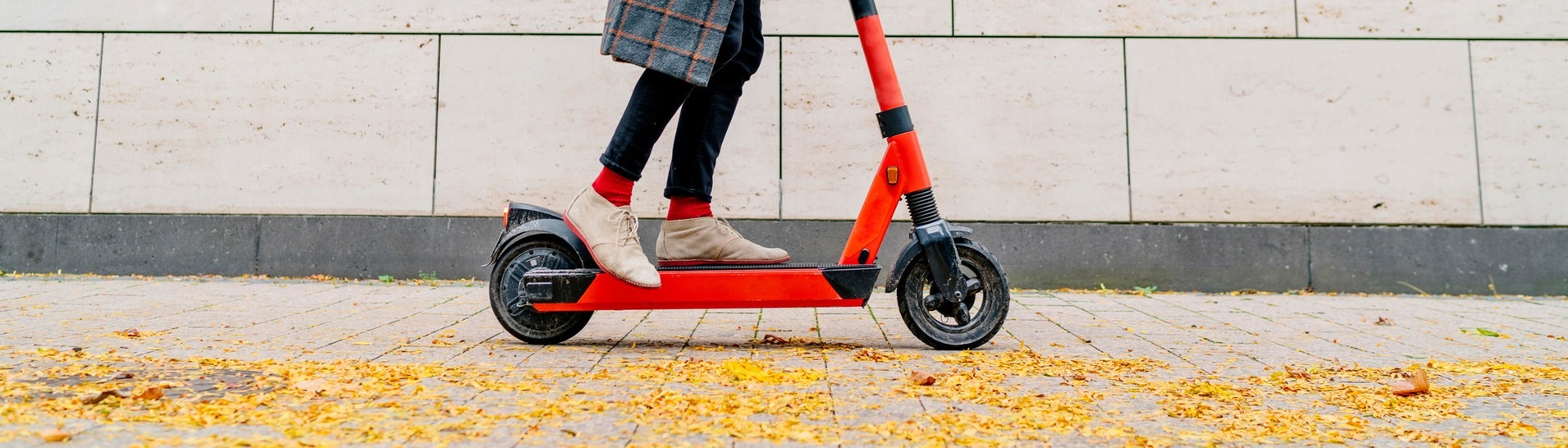 Mann mit E-Scooter auf Bürgersteig vor grauer Wand (Foto: dpa Bildfunk, Picture Alliance)