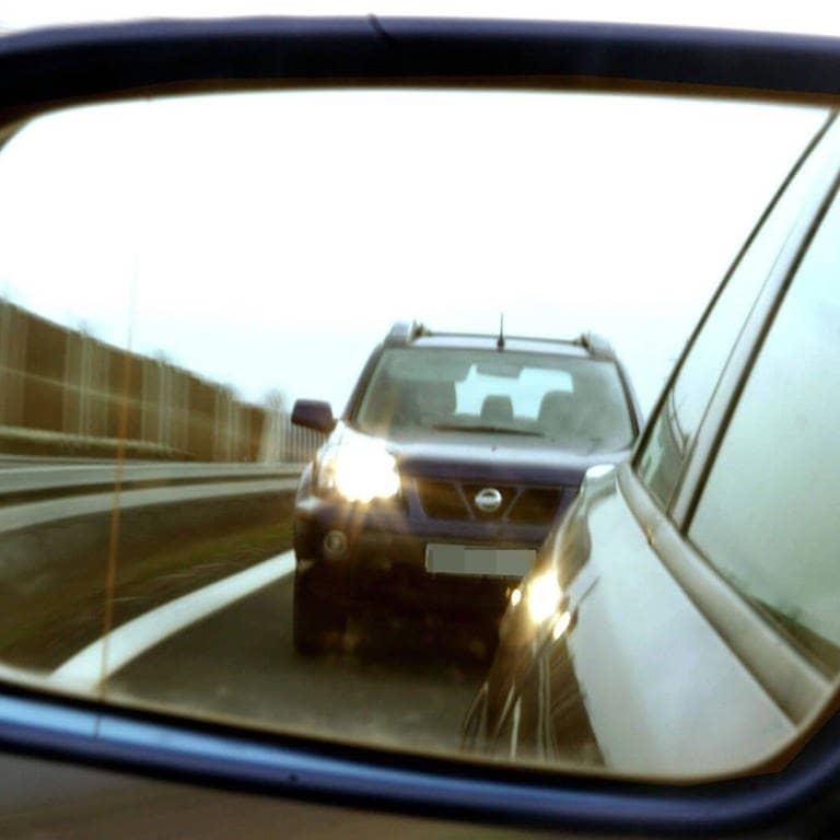 dicht auffahrendes Auto im Außenspiegel, ein so genannter Drängler mit eingeschalteten Scheinwerfern