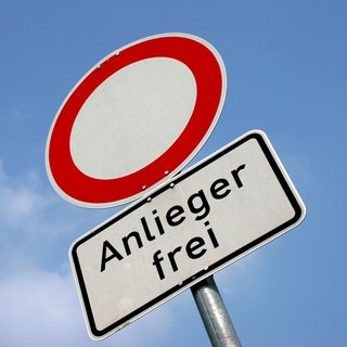 Ein Verkehrzeichen auf dem steht „Anlieger frei“ und das typische Durchfahrt-Verboten-Schild vor blauem Himmel. Was bedeutet aber genau Anlieger frei? 