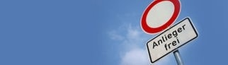 Ein Verkehrzeichen auf dem steht „Anlieger frei“ und das typische Durchfahrt-Verboten-Schild vor blauem Himmel. Was bedeutet aber genau Anlieger frei? 