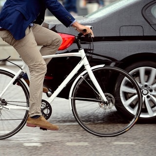 Radfahrer, der von einem Auto überholt wird