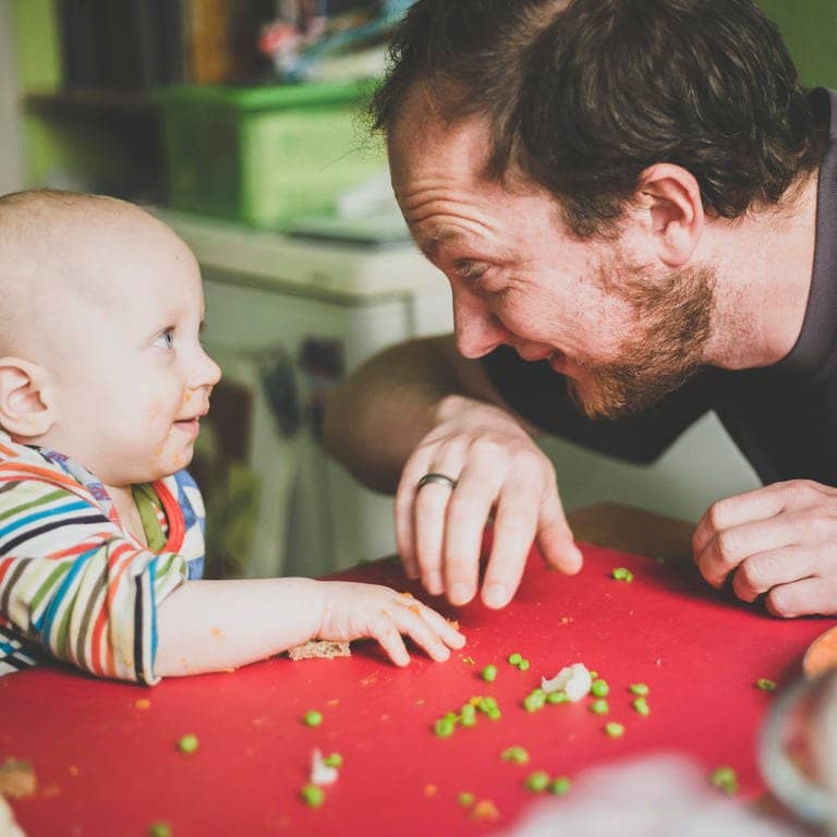 Ein Vater füttert sein Kind mit grünen Erbsen (Foto: picture-alliance / Reportdienste, picture alliance / Westend61 | Irina Heß)