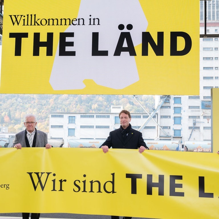 Poltiker halten Banner mit Baden-Württembergs Slogan "The Länd" hoch. (Foto: picture-alliance / Reportdienste, Bernd Weißbrod;)