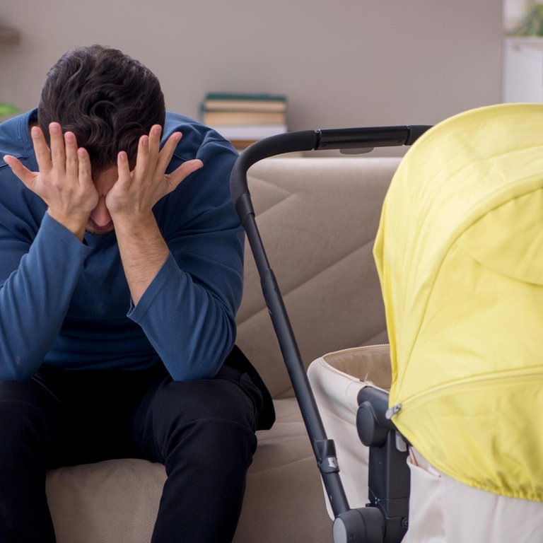 Ein junger Vater sitzt vor einem Kinderwagen und schlägt sich die Hände vor das Gesicht (Foto: picture-alliance / Reportdienste, Elnur Amikishiyev)