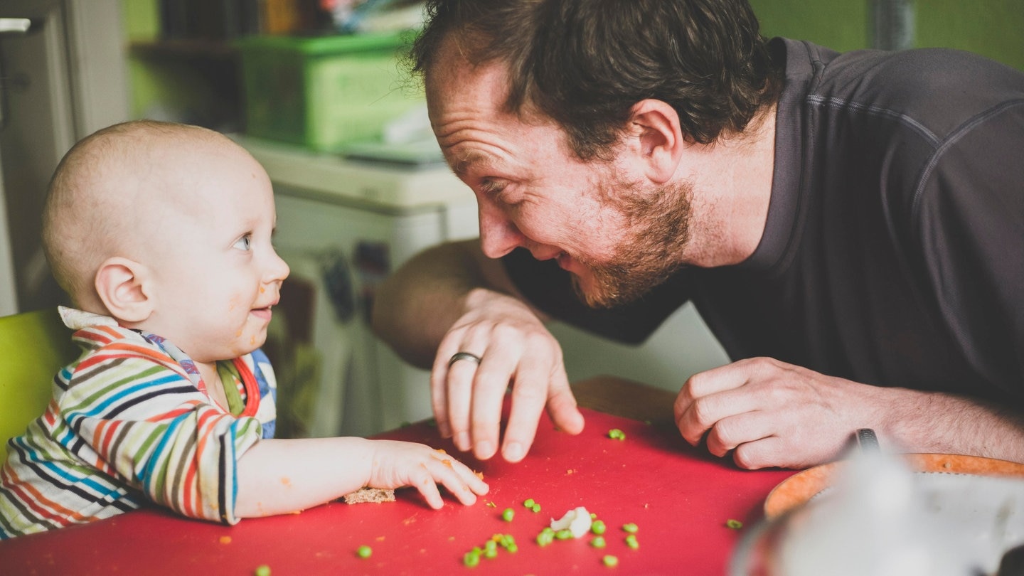 Ein Vater füttert sein Kind mit grünen Erbsen (Foto: picture-alliance / Reportdienste, picture alliance / Westend61 | Irina Heß)