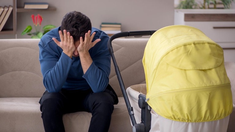 Ein junger Vater sitzt vor einem Kinderwagen und schlägt sich die Hände vor das Gesicht (Foto: picture-alliance / Reportdienste, Elnur Amikishiyev)