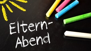 Mit Kreide steht auf einer Schul-Tafel das Wort Elternabend geschrieben. Außerdem ist eine gelbe Sonne aufgemalt, um die Eltern Willkommen zu heißen. (Foto: Adobe Stock, Stockwerk-Fotodesign) Mit Kreide steht auf einer Schul-Tafel das Wort Elternabend geschrieben. Außerdem ist eine gelbe Sonne aufgemalt, um die Eltern Willkommen zu heißen.