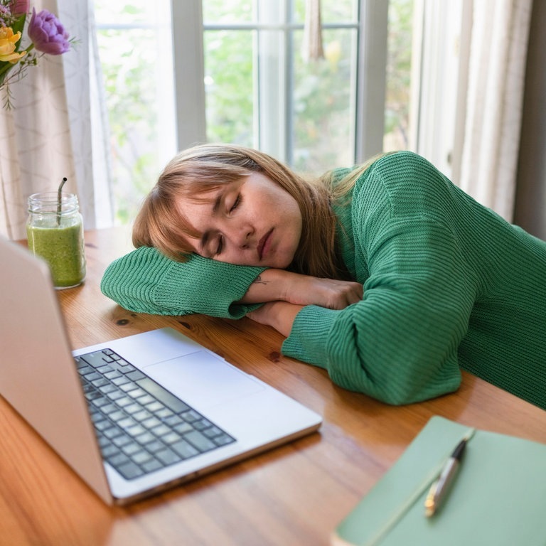 Eine Frau hat ihren Kopf auf dem Arm gestützt und liegt am Tisch vr ihrem Computer, weil sie überfordert ist (Foto: picture-alliance / Reportdienste, picture alliance / Westend61 | Svetlana Karner)