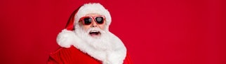 Ein Weihnachtsmann lacht über Flachwitze zu Weihnachten und hält sich lachend den Bauch.