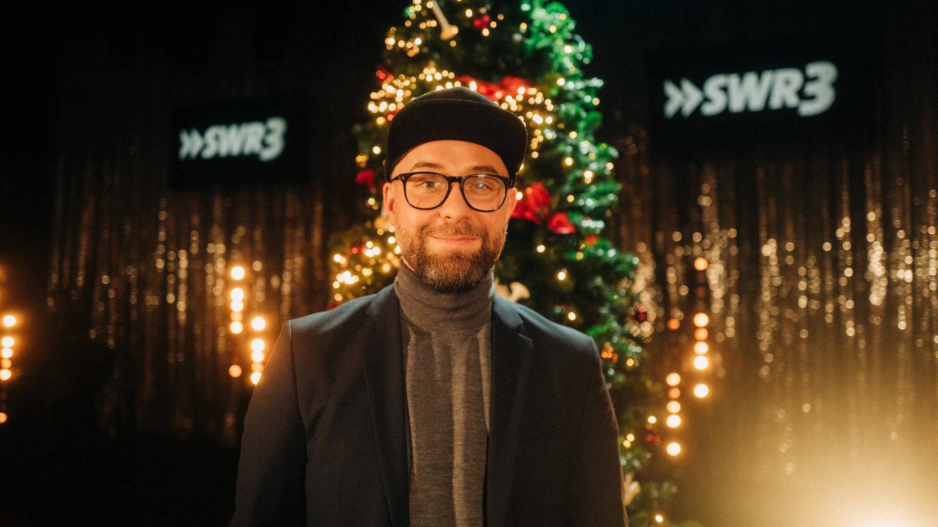 Mark Forster mit Brille und Cap vor Weihnachtsbaum (Foto: SWR3, SWR3/Niko Neithardt)